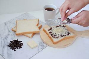 donna di mani fabbricazione crostini con burro e cioccolato su bianca sfondo. foto