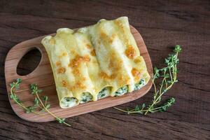 cannelloni con ricotta e spinaci su il di legno tavola foto