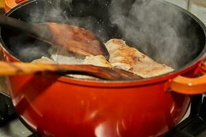 pollo gambe siamo fritte nel padella, di legno bastoni per eccitante e vapore foto