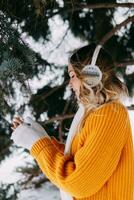 adolescente bionda nel un' giallo maglione al di fuori nel inverno. un' adolescenziale ragazza su un' camminare nel inverno Abiti nel un' nevoso foresta foto