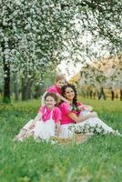 bellissimo mamma e Due figlie nel luminosa Abiti avere divertimento nel il primavera nel il parco foto