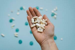 vario medicinale pillole e capsule su un' donna di palma su un' blu sfondo foto