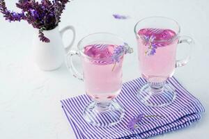 fresco acqua con lavanda nel bicchieri e un' mazzo di fiori nel un' brocca su il tavolo. lavanda aromatico cocktail. copia spazio foto