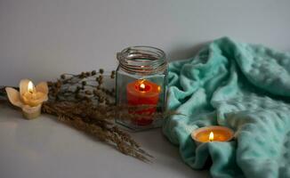 accogliente ardente candela nel Marrone bicchiere barattolo, inverno casa interno arredamento su di legno vassoio con asciutto canna mazzo. eco stile foto