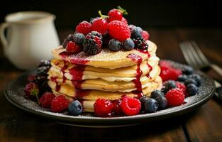 pila di fresco soffice Pancakes decorato su superiore con foresta frutti di bosco rotante su un' piatto e scrosciante miele sciroppo. delizioso, sano. fresco forno concetto. foto