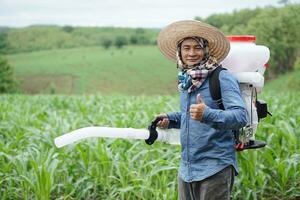 asiatico uomo contadino trasportare fertilizzante spruzzatore macchina su Indietro, In piedi a giardino. concetto, contadino uso motore facilitatore attrezzo nel agricoltura. facile e veloce per semina. foto