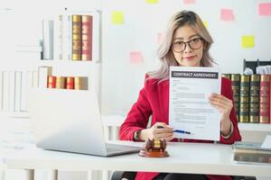 asiatico femmina avvocato o legale consulente firma un' contrarre il contrarre documenti quello opera su il tuo scrivania nel il legge ufficio siamo Là per guida voi. foto