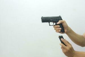 uno mano Tenere il pistola puntamento inoltrare e il altro inserzione il MAG in il pistola su un' bianca sfondo. foto
