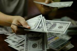 donne d'affari che contano soldi su una pila di banconote da 100 dollari USA us foto