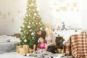 allegro Natale e contento vacanze. famiglia preparazione vicino il natale albero a casa foto