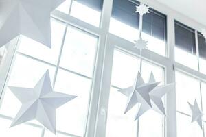un' stella sagomato Natale decorazione pendente contro un' finestra nel luce del giorno. foto