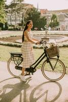 giovane donna con cane bianco bichon frise nel cestino della bici elettrica foto