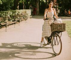 giovane donna con cane bianco bichon frise nel cestino della bici elettrica foto