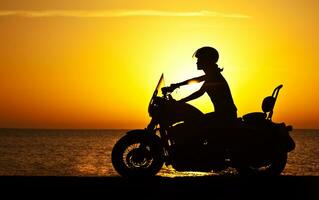 donna motociclista al di sopra di tramonto foto