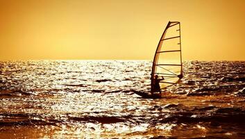 windsurfista silhouette al di sopra di mare tramonto foto