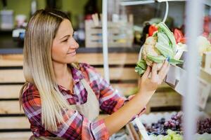 donna lavori nel frutta e verdure negozio. lei è l'esame merce. foto