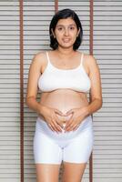 ritratto di un' incinta donna toccante sua grande pancia vicino su, madre, gravidanza, persone e aspettativa. donna Tenere grande incinta stomaco foto