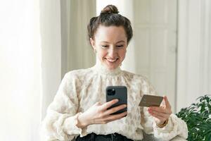 il donna usi un' banca carta per pagare per in linea acquisti, il memorizzare App nel il Telefono. foto
