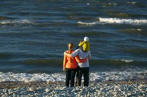 giovane famiglia godendo un' giorno a il mare foto