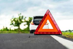 problemi con l'auto e un triangolo rosso segnale di pericolo sulla strada foto