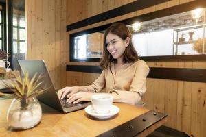 bella donna d'affari sta lavorando con il suo computer portatile in caffetteria foto