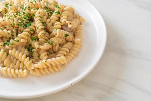 spirali o pasta a spirale salsa di crema di funghi con prezzemolo - stile alimentare italiano