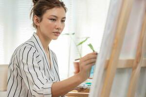 bellissimo femmina Hobby di artista e uso pennello nel astratto arte per creare capolavoro. pittore dipingere con acquerelli o olio nel studio Casa. godere pittura come passatempo, ricreazione, ispirazione foto