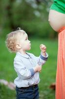 carino poco ragazzo guardare a incinta mamme pancia foto