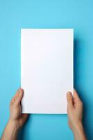 un' umano mano Tenere un' vuoto foglio di bianca carta o carta isolato su blu sfondo. ai generato foto