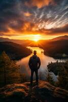 uomo in piedi in cima montagna ammirazione tramonto al di sopra di lago foto