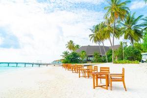 tavolo e sedia in legno vuoto sulla spiaggia con sfondo vista mare alle maldive foto