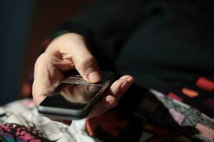 vecchio donna è andando per comporre un' numero su sua cellula Telefono foto