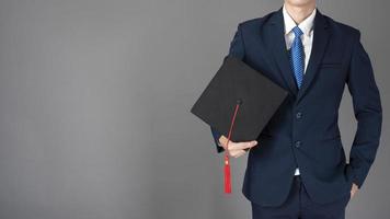 l'uomo d'affari tiene in mano il cappello di laurea, concetto di educazione aziendale foto