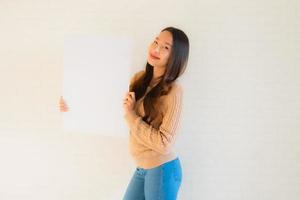 le belle giovani donne asiatiche del ritratto mostrano il cartone bianco vuoto foto