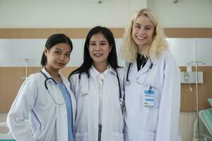 professionale medico personale squadra, tre bianca in uniforme femmina medici guardare a telecamera, allegro e sorridente, contento fisico opera occupazione nel ospedale clinica. foto