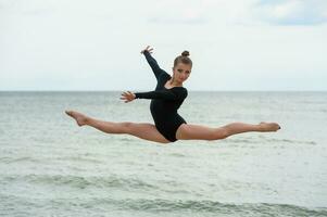 ginnasta ballerino salto su il mare spiaggia foto