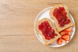 pane integrale fatto in casa con marmellata di fragole e fragole fresche foto