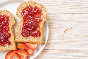 pane integrale fatto in casa con marmellata di fragole e fragole fresche foto