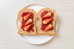 pane integrale fatto in casa con marmellata di fragole e fragole fresche foto