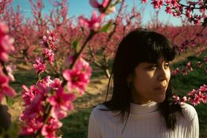 donna tra il bella rosa pesca albero fiori. foto