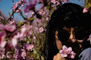 donna tra il bella rosa pesca albero fiori. foto