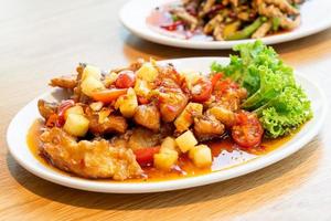 pesce cernia fritto condito con salsa dolce, acida e piccante su piatto bianco - stile cibo asiatico foto