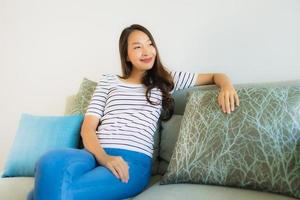 ritratto bella giovane donna asiatica sorriso felice sul divano foto