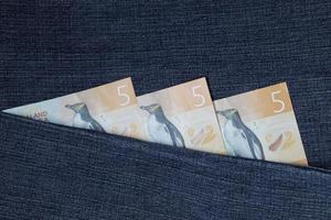 banconote neozelandesi da cinque dollari tra tessuto denim blu foto