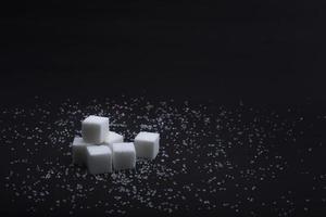 zollette di zucchero bianco su sfondo nero foto