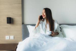 ritratto belle giovani donne asiatiche sorriso felice con caffè e telefono cellulare foto