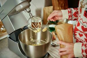 donna cucinando a casa cucina, uso elettrico miscelatore per preparazione Impasto foto