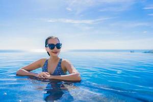 ritratto bella giovane donna asiatica sorriso felice relax intorno alla piscina in hotel resort con vista mare e oceano