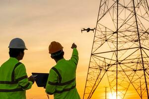 ingegneri Posizione Aiuto tecnico uso fuco per volare ispezioni a il elettrico energia stazione per Visualizza il pianificazione opera di producendo elettricità alto voltaggio elettrico trasmissione Torre a tramonto foto