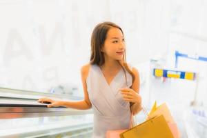 ritratto bella giovane donna asiatica felice e sorridere con la borsa della spesa dal grande magazzino foto